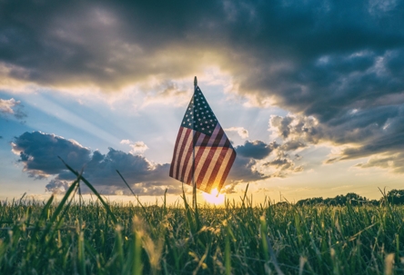 American flag in field at sunset