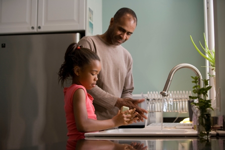 father with daughter at kitchen sink