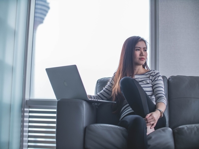 woman on couch looking away from computer